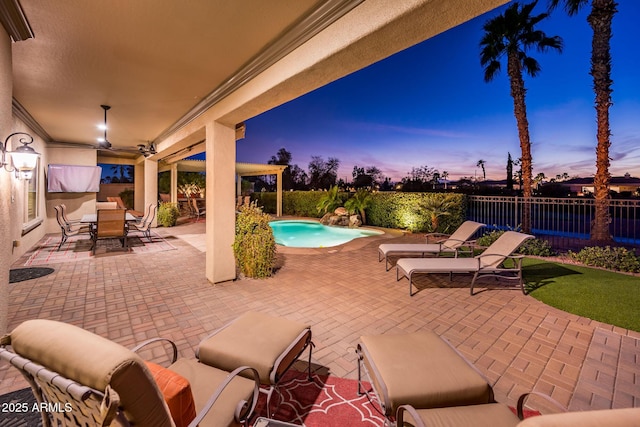 patio terrace at dusk featuring outdoor dining area, a fenced in pool, and fence