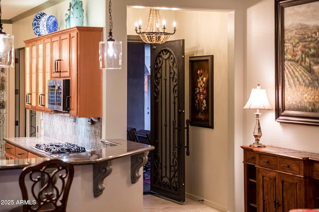 kitchen with ornamental molding, decorative backsplash, appliances with stainless steel finishes, decorative light fixtures, and a chandelier