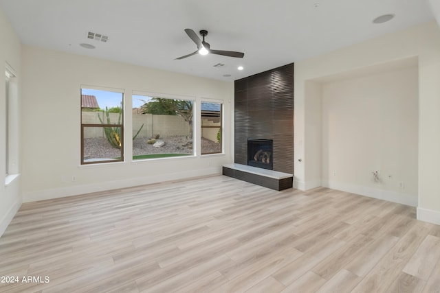 unfurnished living room featuring a fireplace, light wood-type flooring, and ceiling fan