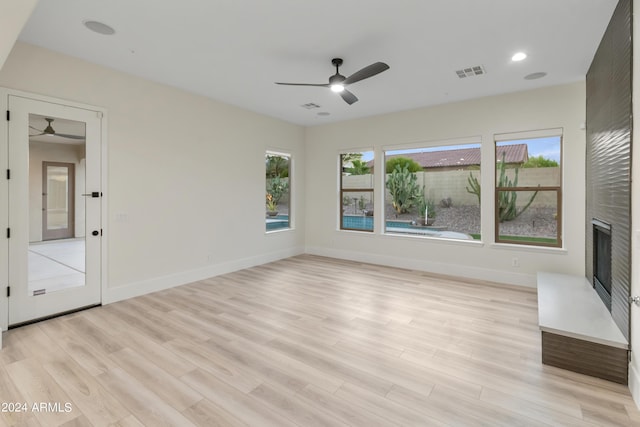 unfurnished living room with light hardwood / wood-style floors, ceiling fan, and plenty of natural light