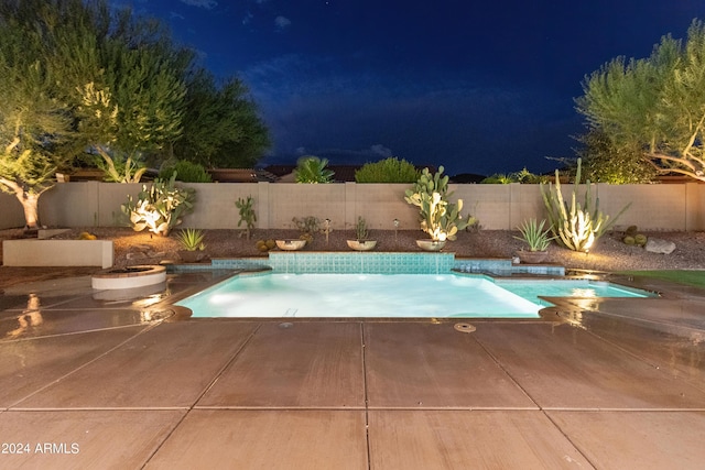 pool at twilight with pool water feature and a patio area