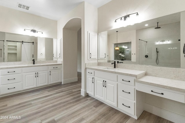 bathroom with a tile shower, vanity, and hardwood / wood-style floors