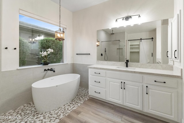 bathroom featuring tile walls, separate shower and tub, vanity, and wood-type flooring