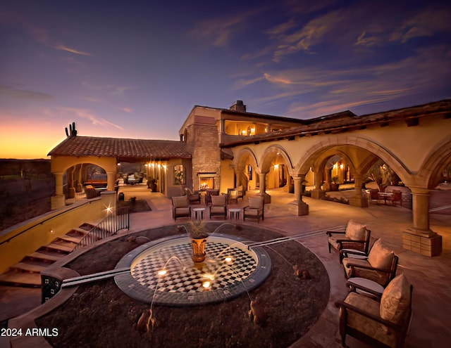 patio terrace at dusk with an outdoor living space with a fire pit