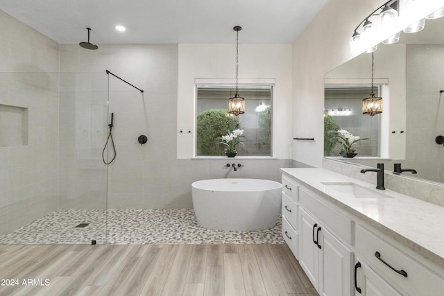 bathroom with wood-type flooring, vanity, and independent shower and bath