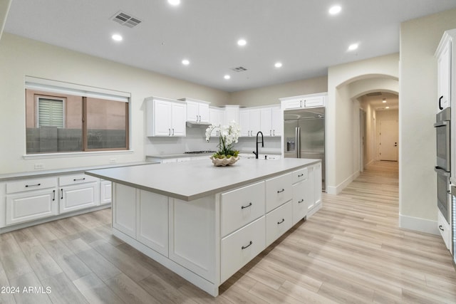 kitchen with sink, white cabinets, a kitchen island with sink, and light hardwood / wood-style flooring