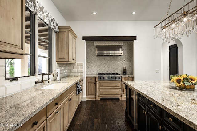 kitchen featuring decorative backsplash, light stone countertops, wall chimney exhaust hood, dark wood-type flooring, and sink