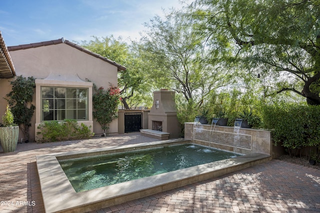 view of swimming pool with a patio and exterior fireplace