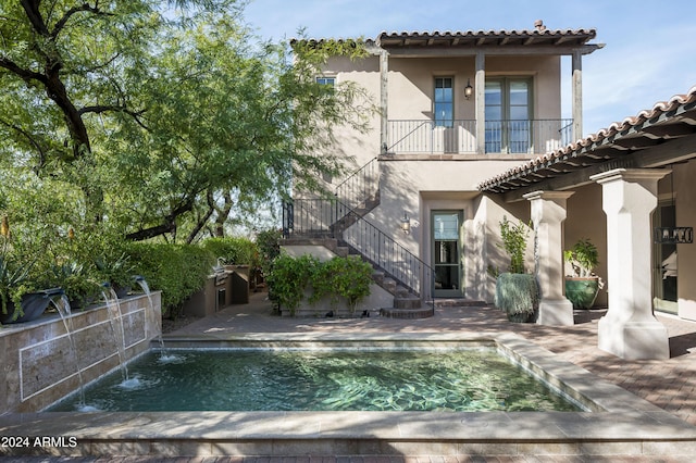 back of house featuring pool water feature, a balcony, and a patio area