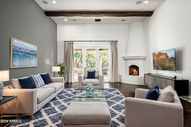 living room featuring beamed ceiling, dark hardwood / wood-style floors, and a large fireplace