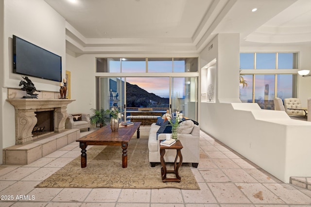 living room with a towering ceiling, a mountain view, a raised ceiling, and a tile fireplace