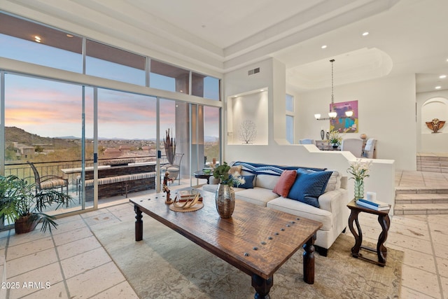 living room with a raised ceiling, a high ceiling, and an inviting chandelier