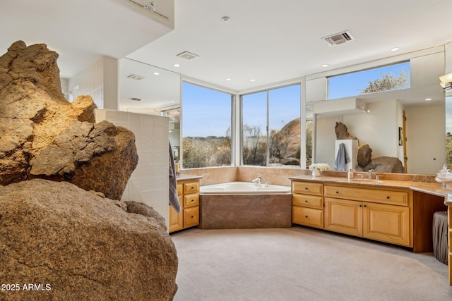 bathroom with vanity and tiled bath