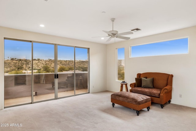 sitting room with ceiling fan, light carpet, and a wealth of natural light