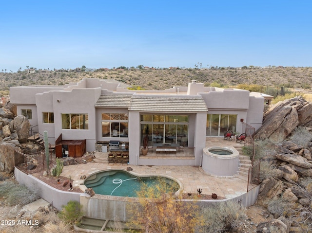 rear view of property featuring a swimming pool with hot tub and a patio area