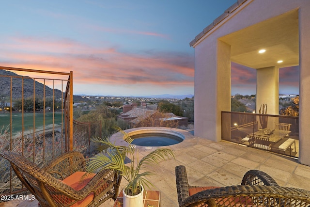 patio terrace at dusk featuring a mountain view and an in ground hot tub