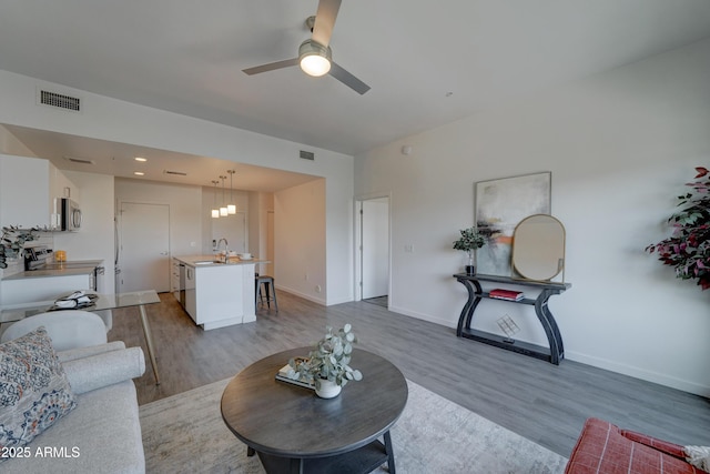 living room with ceiling fan, sink, and light hardwood / wood-style flooring