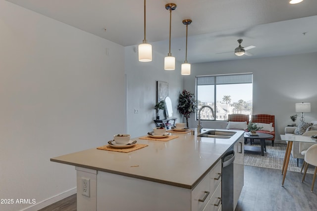 kitchen with sink, hanging light fixtures, dark hardwood / wood-style flooring, an island with sink, and white cabinets