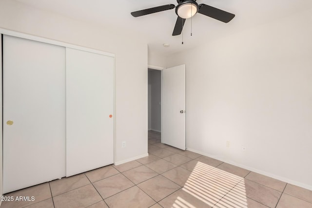 unfurnished bedroom with a ceiling fan, a closet, baseboards, and light tile patterned floors