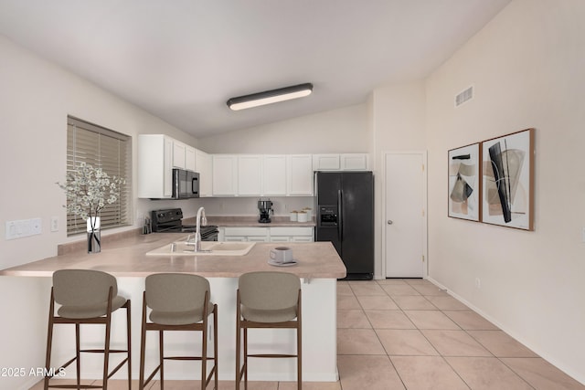 kitchen with light tile patterned floors, a peninsula, a sink, visible vents, and black appliances