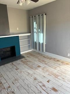 unfurnished living room with light wood-type flooring and ceiling fan