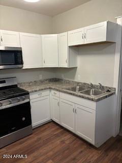 kitchen with dark hardwood / wood-style flooring, appliances with stainless steel finishes, sink, and white cabinets