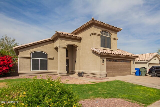 mediterranean / spanish house featuring stucco siding, a tiled roof, and concrete driveway