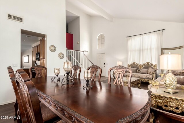 dining area featuring beam ceiling, high vaulted ceiling, stairs, wood finished floors, and visible vents