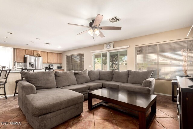living area with a ceiling fan, baseboards, visible vents, and light tile patterned floors