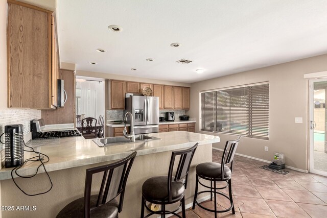 kitchen with decorative backsplash, visible vents, a sink, a peninsula, and stainless steel appliances