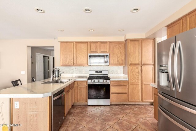 kitchen with decorative backsplash, appliances with stainless steel finishes, a sink, light countertops, and a peninsula