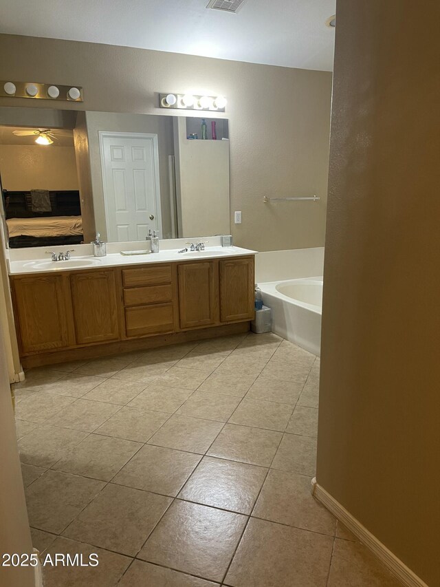 ensuite bathroom featuring double vanity, ceiling fan, a bath, tile patterned floors, and a sink