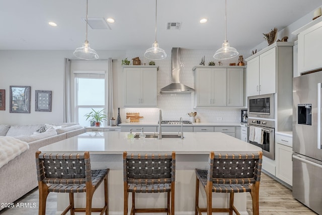 10509 W Harmony Ln, Peoria, AZ 85382 - kitchen featuring appliances with stainless steel finishes, wall chimney exhaust hood, a breakfast bar, tasteful backsplash, and light countertops