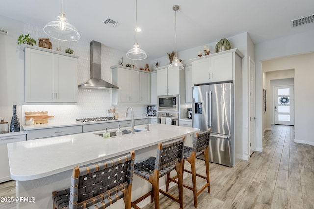 10509 W Harmony Ln, Peoria, AZ 85382 - kitchen featuring appliances with stainless steel finishes, wall chimney exhaust hood, a sink, decorative backsplash, and light countertops