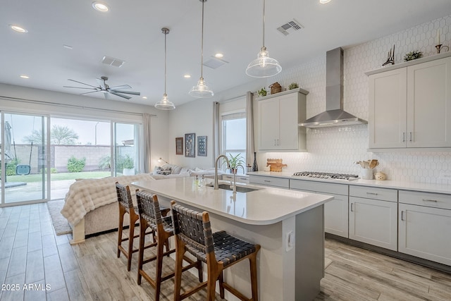 10509 W Harmony Ln, Peoria, AZ 85382 - kitchen featuring wall chimney exhaust hood, a sink, light wood-style flooring, light countertops, and open floor plan