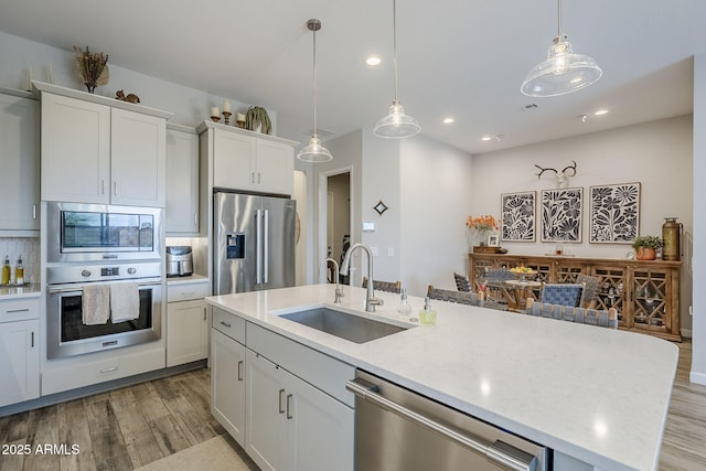 10509 W Harmony Ln, Peoria, AZ 85382 - kitchen with appliances with stainless steel finishes, a sink, light wood finished floors, a kitchen island with sink, and recessed lighting