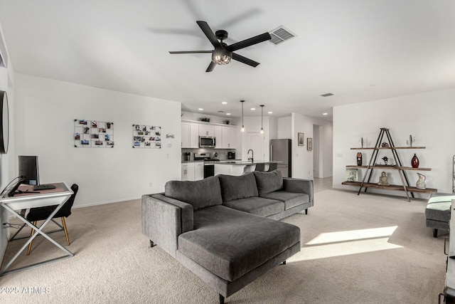 living room featuring ceiling fan, light colored carpet, and sink