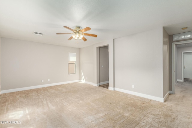 unfurnished room with visible vents, light carpet, baseboards, and a ceiling fan