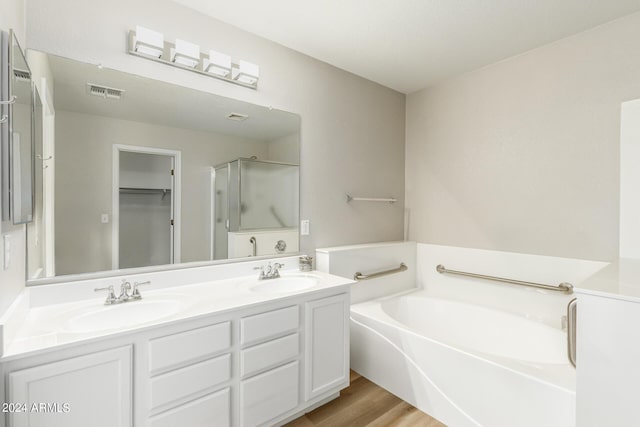 bathroom with double vanity, a bath, visible vents, and a sink