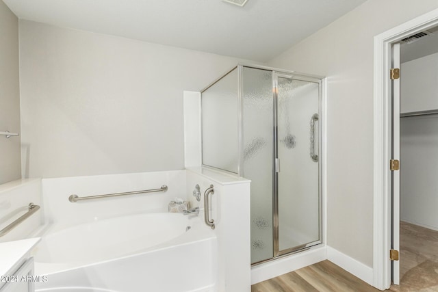 bathroom featuring a bath, wood finished floors, and a stall shower