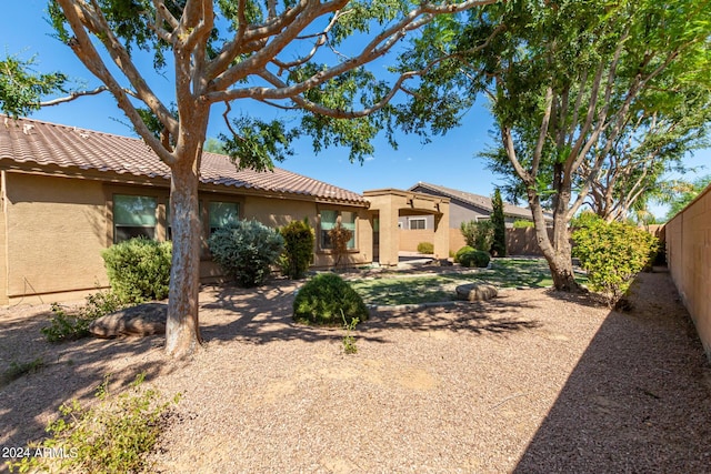 view of front facade featuring a tiled roof, stucco siding, and fence