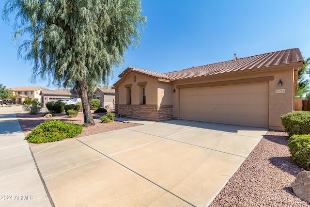 mediterranean / spanish-style house with a tile roof, concrete driveway, a garage, and stucco siding