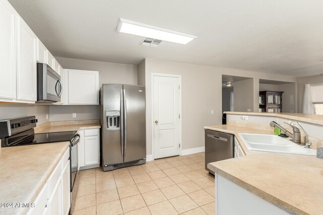 kitchen featuring appliances with stainless steel finishes, light tile patterned floors, white cabinetry, and sink