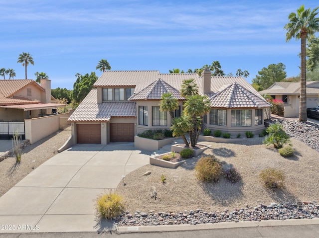 view of front of property featuring stucco siding, a tile roof, fence, concrete driveway, and an attached garage