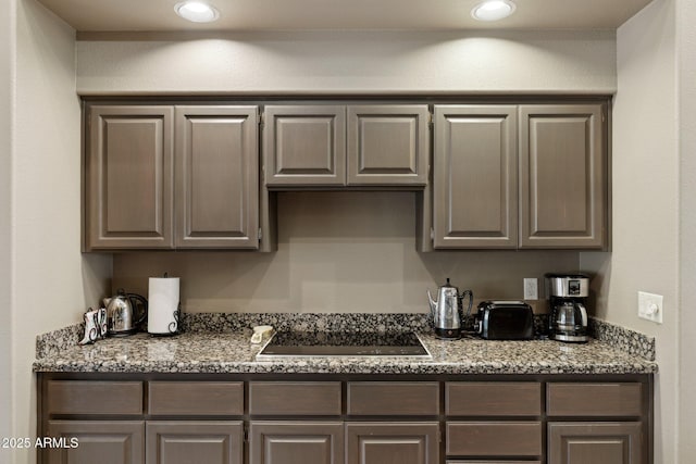 kitchen with light stone counters, recessed lighting, and black electric stovetop