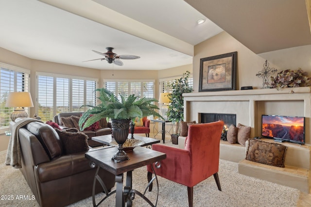 living room with recessed lighting, a fireplace with raised hearth, and a ceiling fan