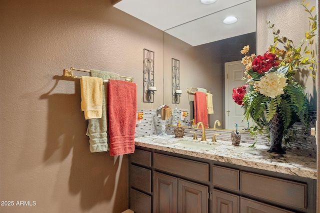 bathroom featuring backsplash, vanity, and a textured wall