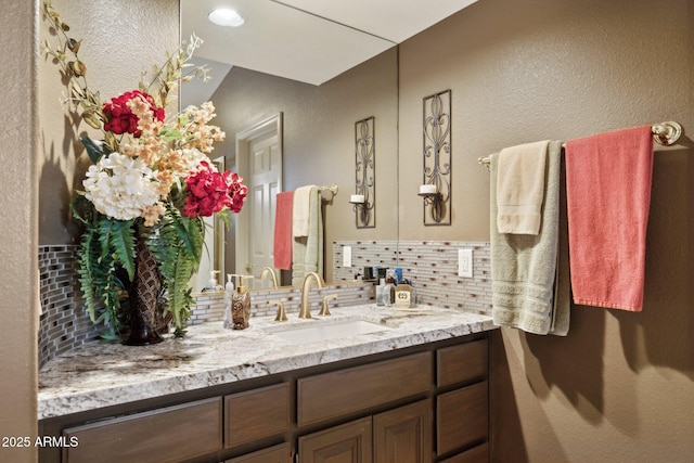 bathroom with tasteful backsplash, vanity, and a textured wall