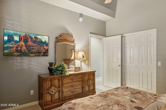 bedroom with a closet, light colored carpet, baseboards, and ceiling fan