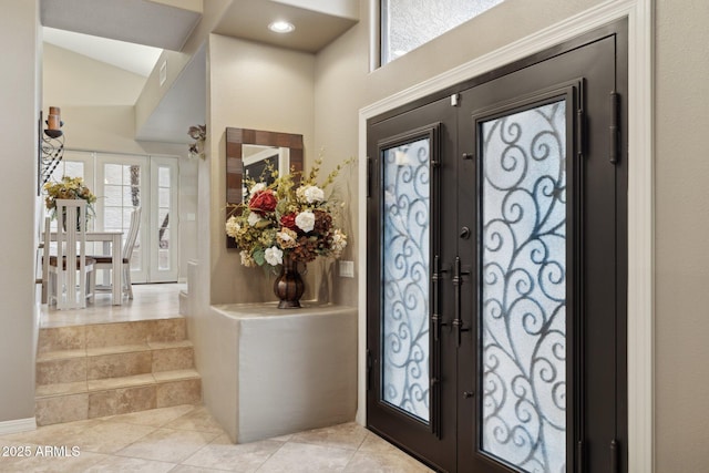 foyer entrance with light tile patterned floors, french doors, and lofted ceiling